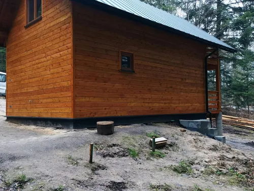 Tylna ściana domu drewnianego z małym oknem i blaszanym dachem