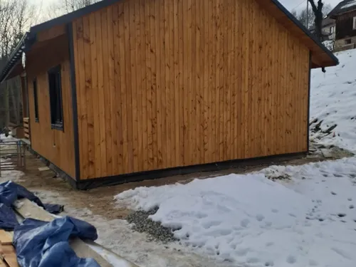 Szczytowa ściana domu drewnianego z pionową elewacją z drewna, zimą