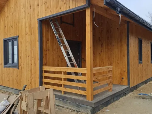 Zadaszona weranda z drewnianą balustradą przy wejściu do domu