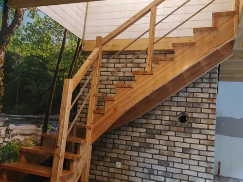 Drewniane schody z balustradą przy ceglanej ścianie i boazerii